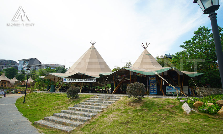 Tipi tent structure with conical frame and extended eaves at resort entrance