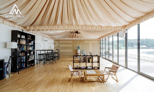 Glamping lounge tent interior with lounge seating, bar tables and bookshelf