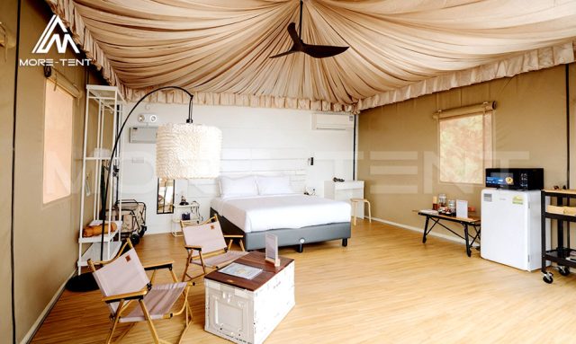 Glamping suite interior with large bed, draped fabric ceiling and leisure furniture