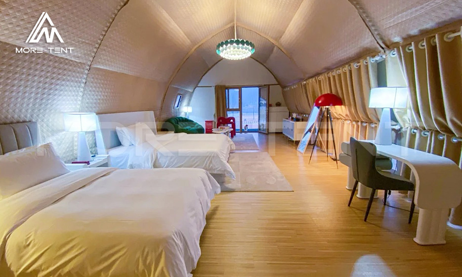Spacious glamping tent interior with twin beds and a curved ceiling