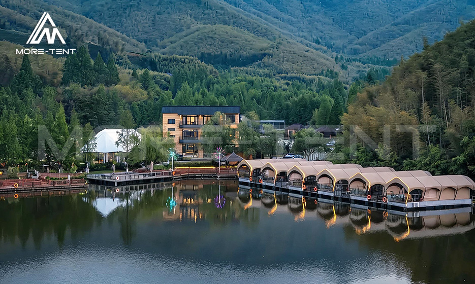 Waterfront glamping tents reflected on a calm lake at dusk