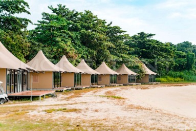 Luxury safari tents lined along the beachfront at a coastal glamping resort