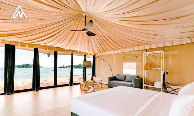 Safari tent suite interior with panoramic ocean view through floor-to-ceiling glass walls