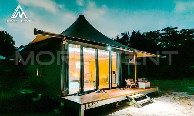 Safari tent suite glowing with warm interior lighting on its wooden deck at night