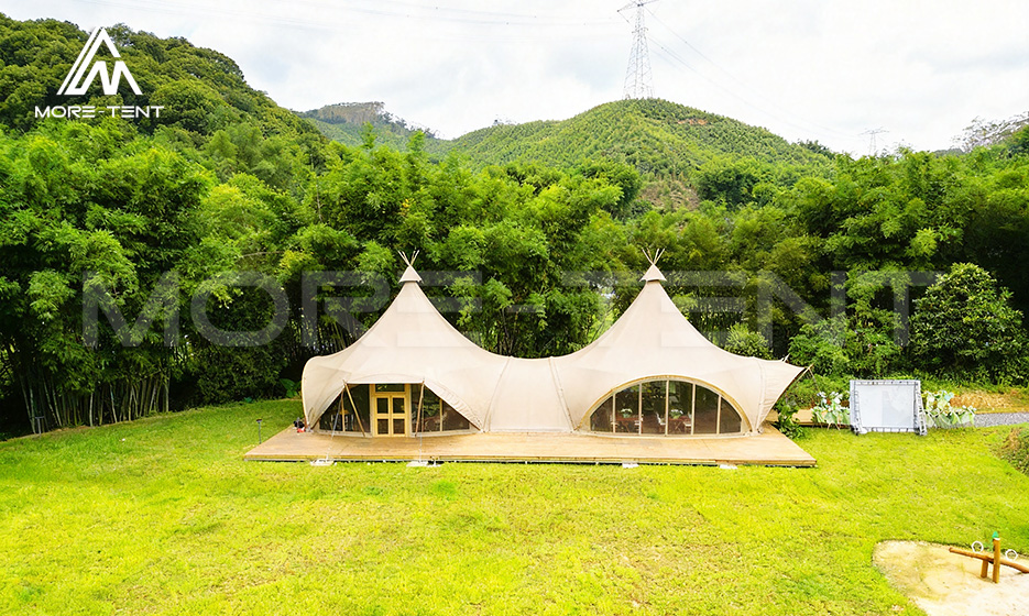 Twin peak tipi glamping tent set against a green bamboo forest