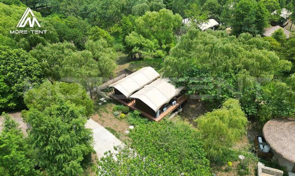 Vista aérea de modernas tiendas de glamping en un complejo turístico rodeado de vegetación.
