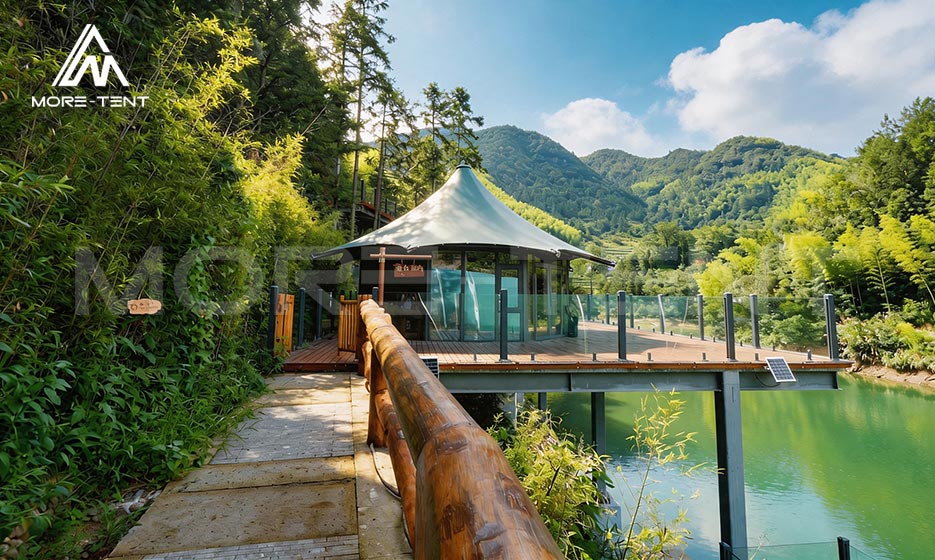 Mountain glamping tent beside a lake with a panoramic resort deck