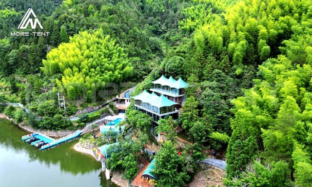 Aerial view of a glamping resort beside a forest lake