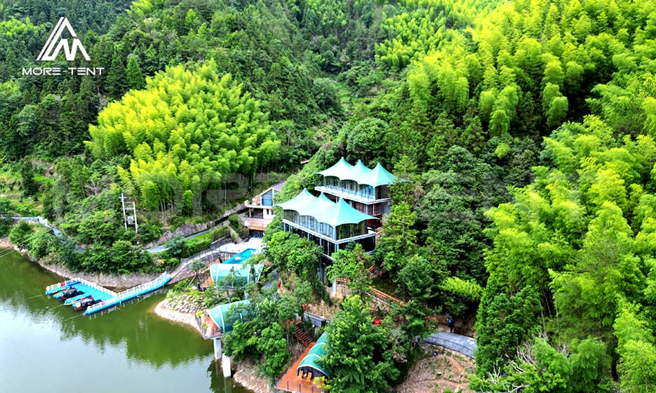 Aerial view of a glamping resort beside a forest lake