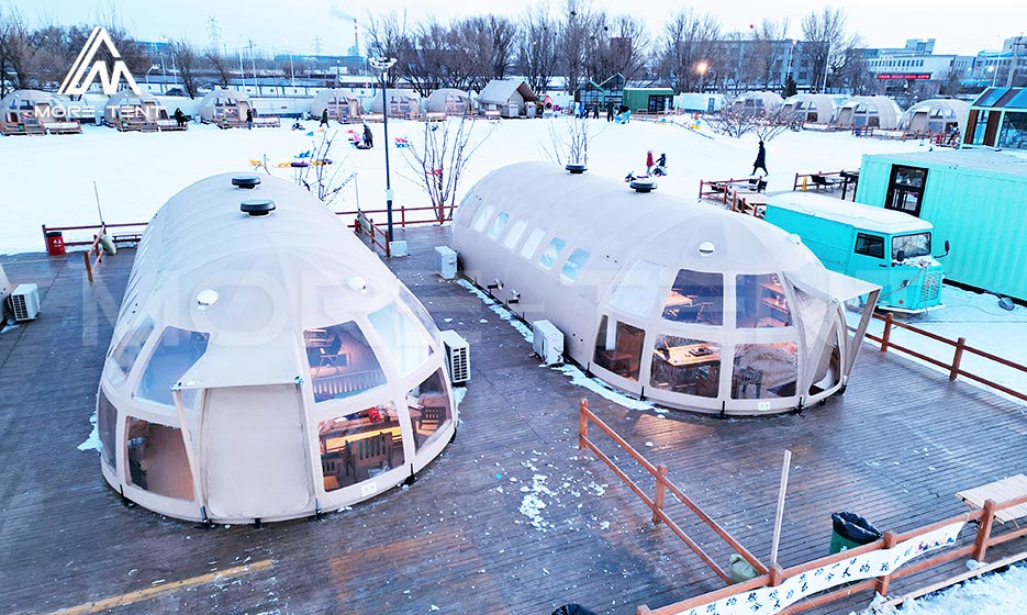 Dome glamping tents on raised decks at a snowy campsite