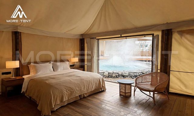Glamping tent bedroom with wicker seating beside a hot spring pool