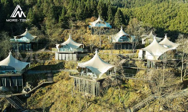 Glamping tents on hillside platforms at a forest resort