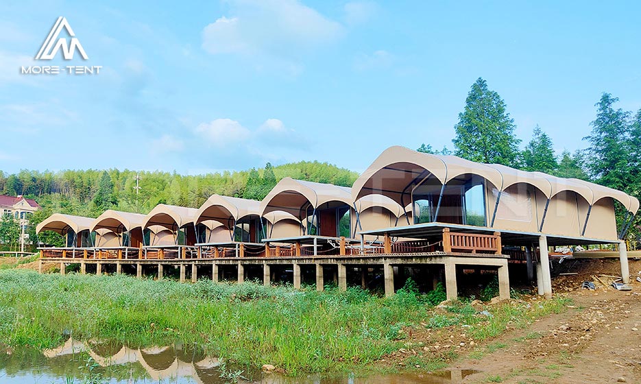 Row of modular glamping tent rooms beside a lake